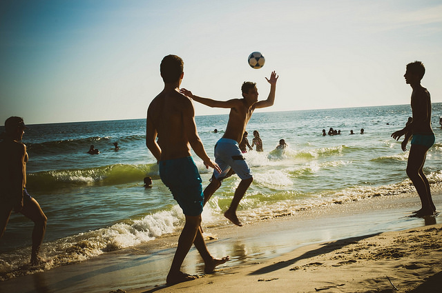 Teenagers playing soccer on the beach