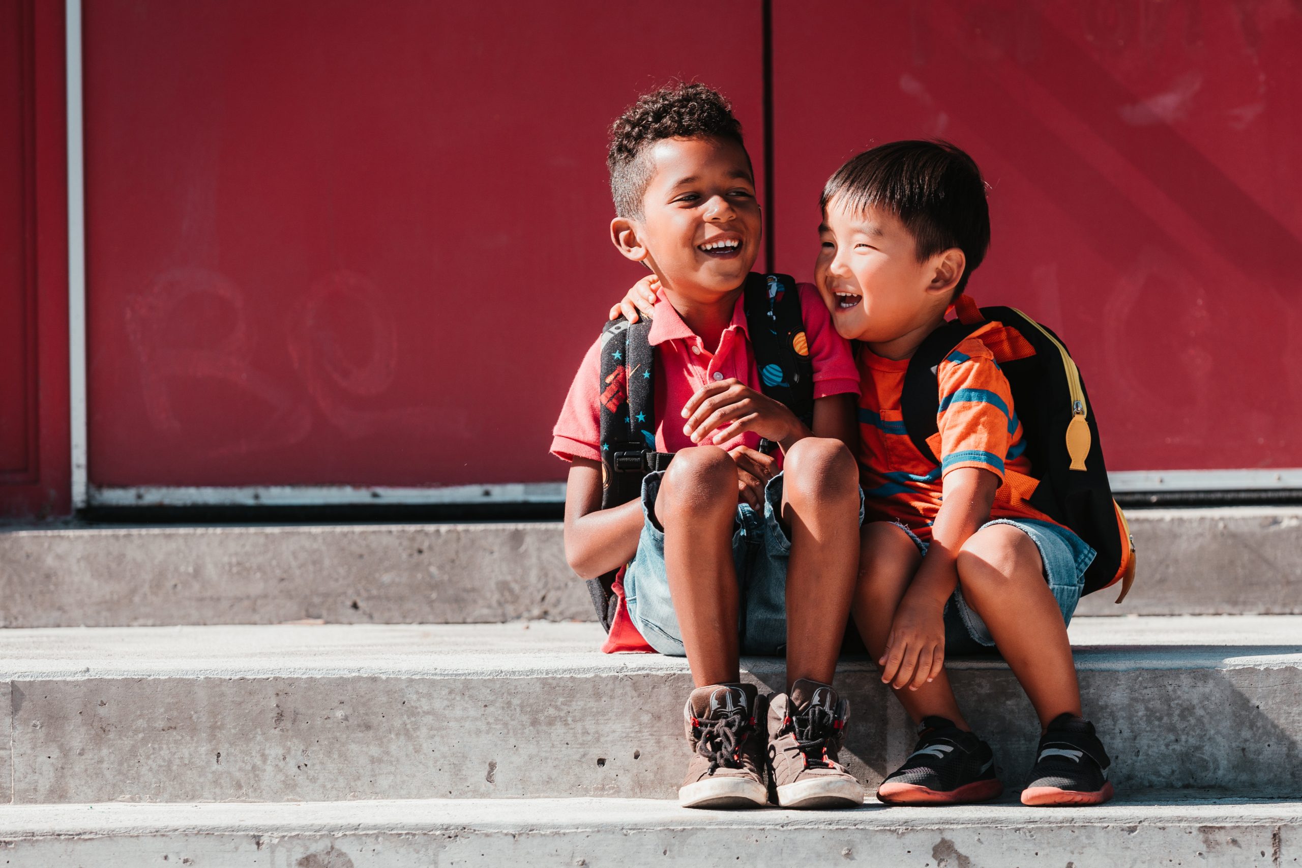 Two school kids laughing on steps.